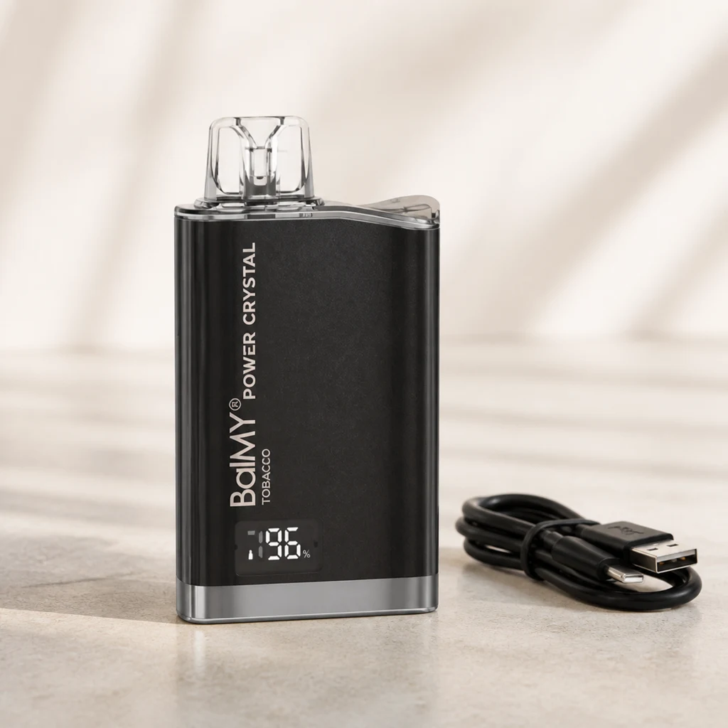 Balmy Power Crystal Tobacco negro con boquilla transparente, pantalla y cable USB al lado, sobre una superficie beige en una escena generada.
