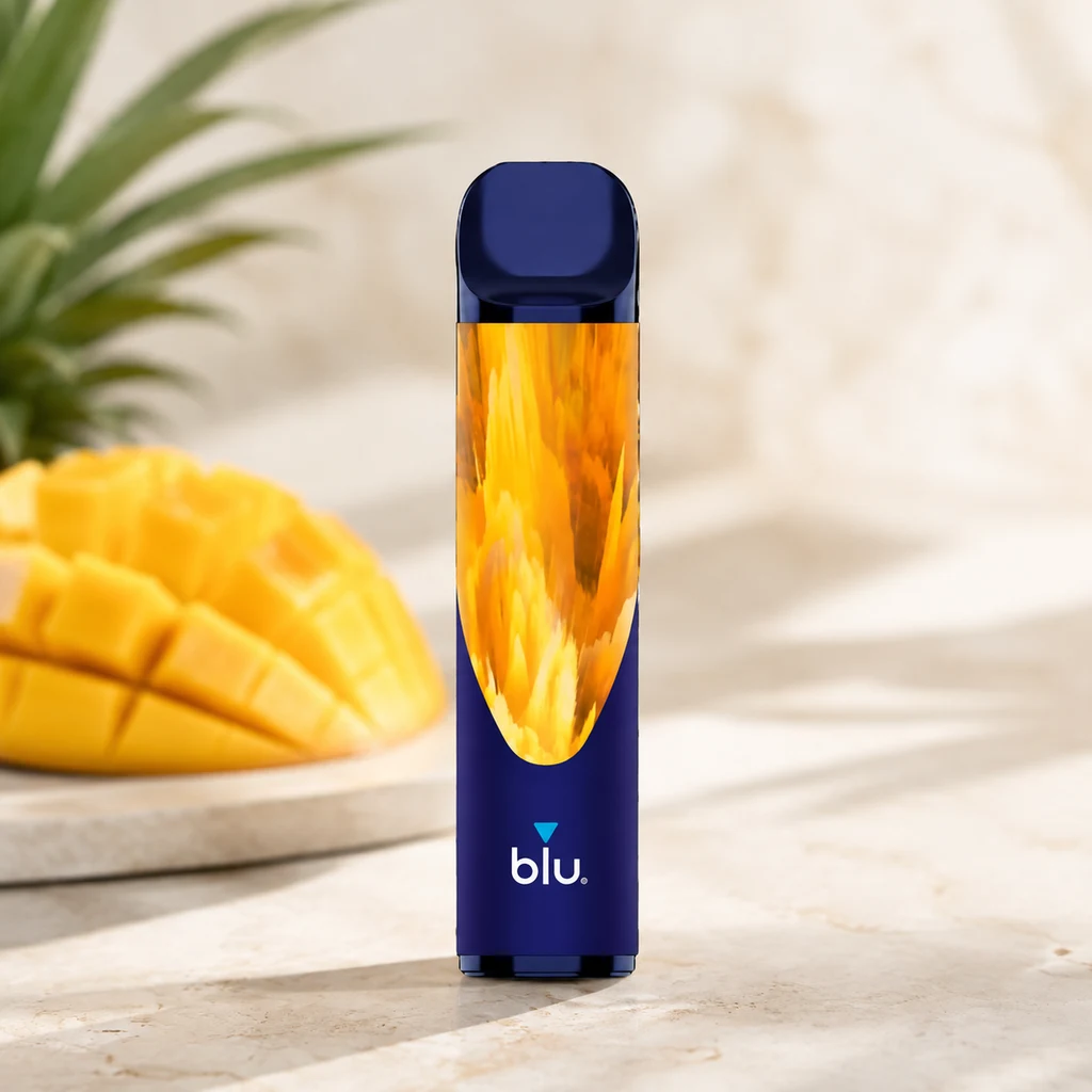 Vaper Blu Bar Tropical Mix 600 azul con motivo amarillo y naranja, de pie sobre una superficie clara junto a mango cortado y hojas de piña.