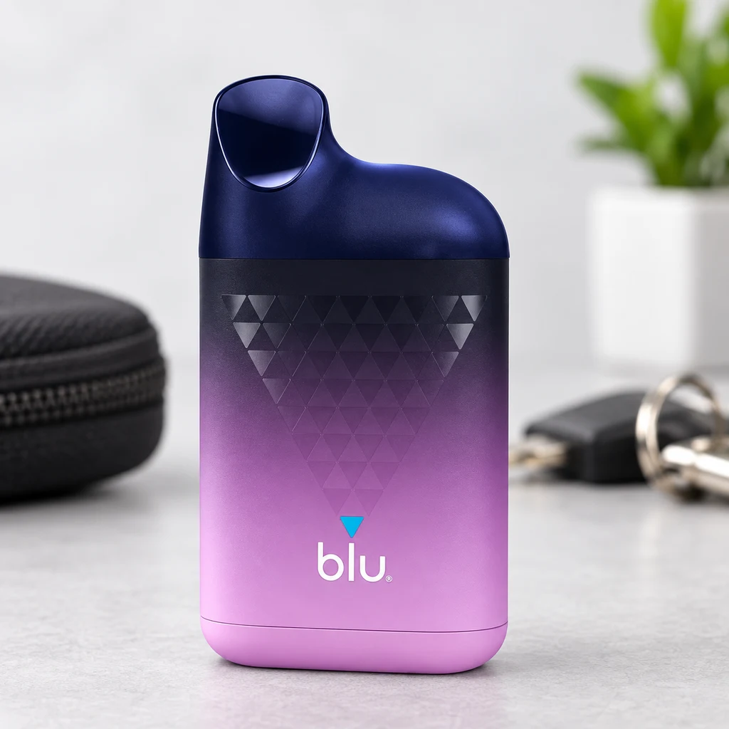 Vaper Blu Box con degradado de negro a rosa, boquilla azul oscuro y dibujo de triángulos, de pie junto a un estuche y unas llaves.