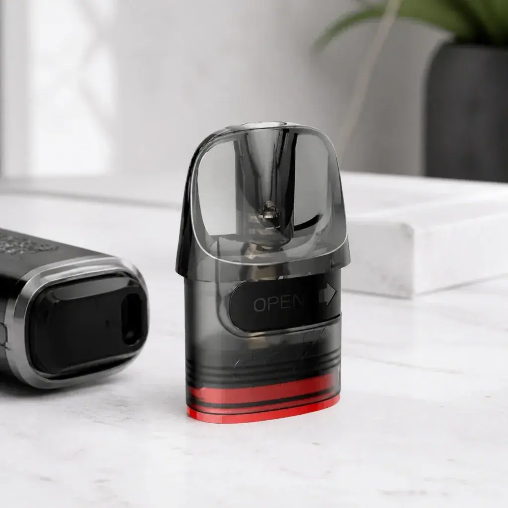 Cartucho Lost Vape E Plus Dual translúcido oscuro, con base roja y pestaña «OPEN», junto a un dispositivo parcialmente visible.