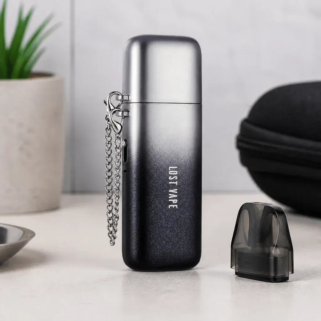 Vapeador Lost Vape con acabado degradado de plateado a negro, tapa y cadena lateral, junto a un cartucho oscuro separado.