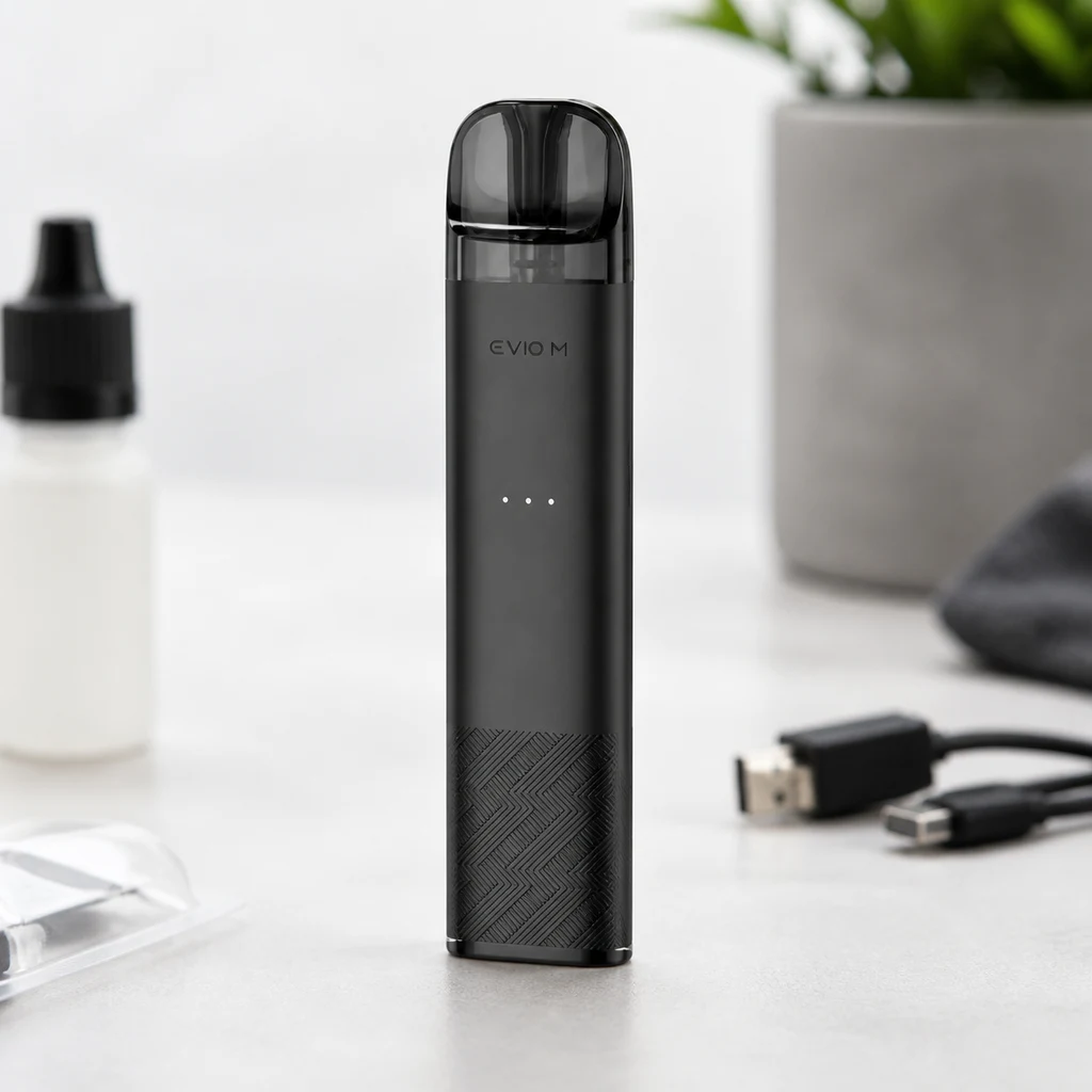 Escena generada del Joyetech Evio M negro en vertical, con boquilla oscura y luces frontales, junto a un frasco y un cable USB sobre una mesa.