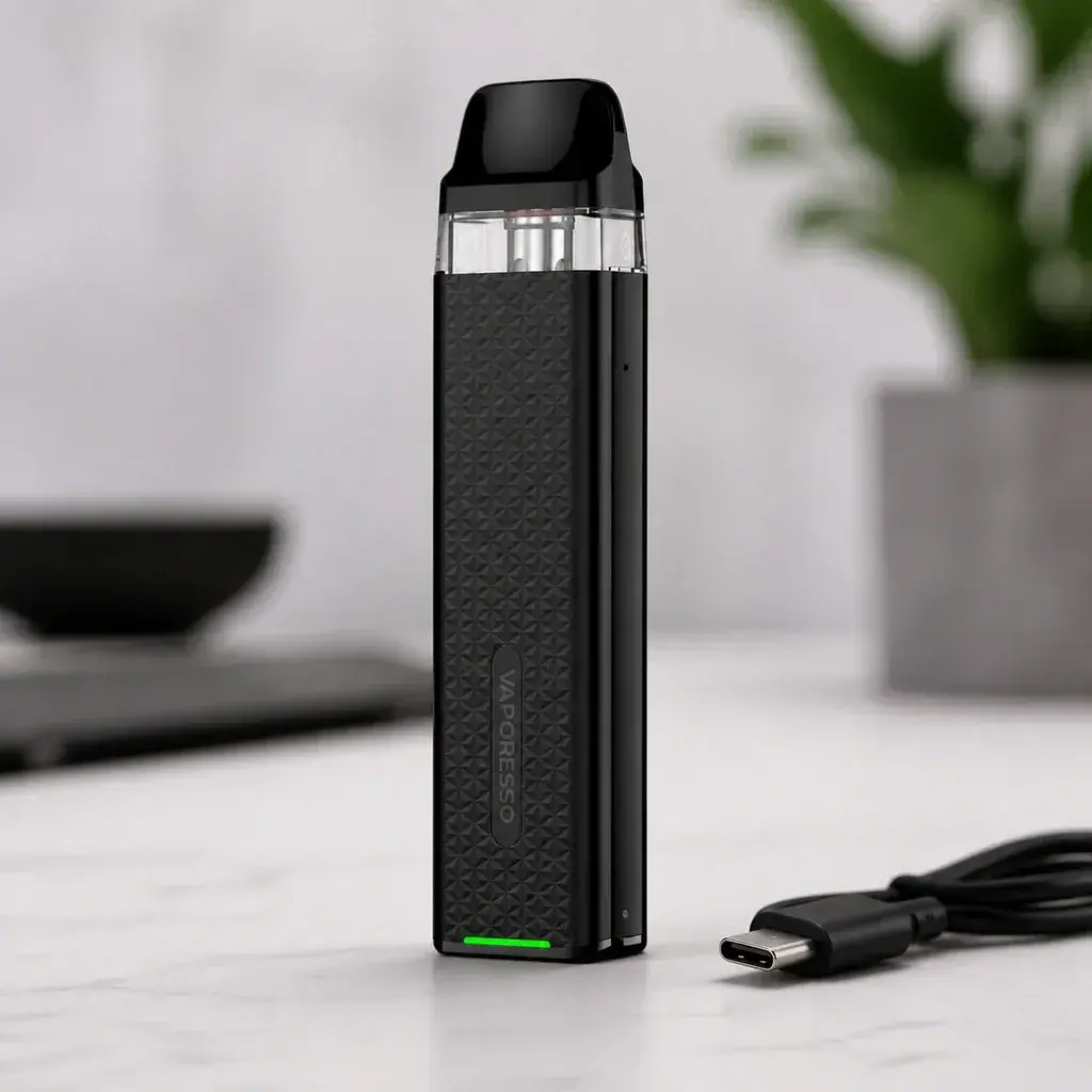 Pod Vaporesso Xros 3 Mini Black de pie, con frontal negro texturizado, depósito transparente y luz verde, junto a un cable USB-C.