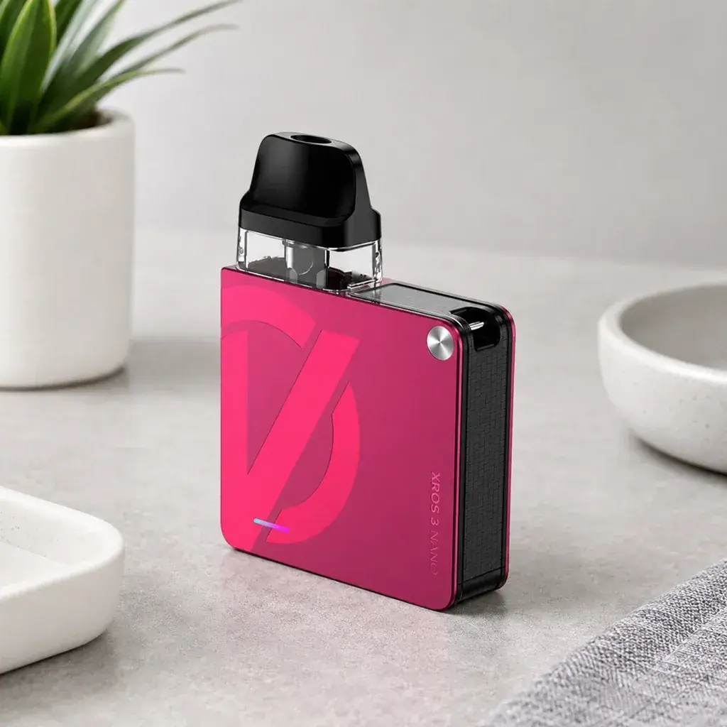 Vaporesso Xros 3 Nano rosa, de cuerpo cuadrado con lateral negro, depósito transparente y boquilla negra, sobre una superficie gris.