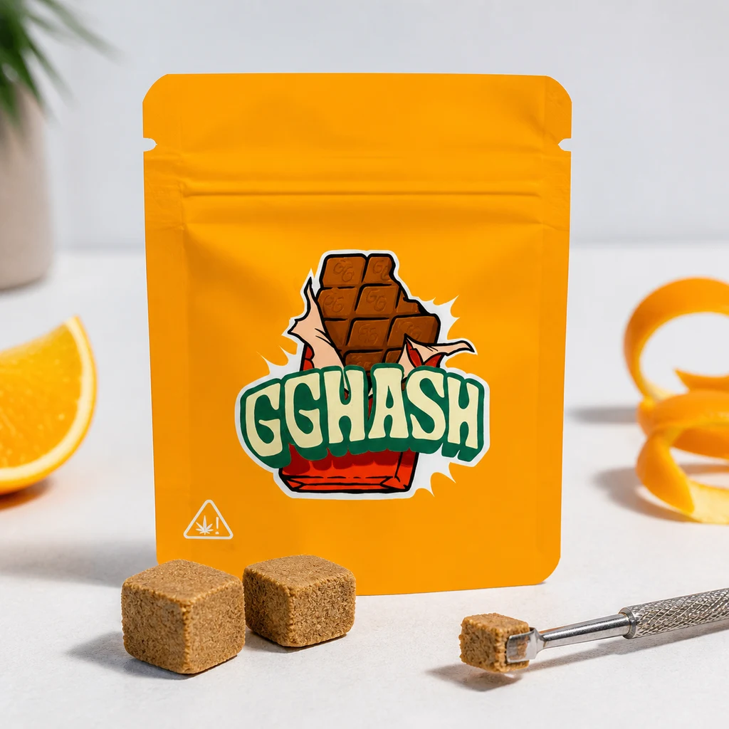 Bolsa naranja GG HASH junto a dos bloques marrones, una pequeña porción en una herramienta metálica, un gajo y tiras de piel de naranja.