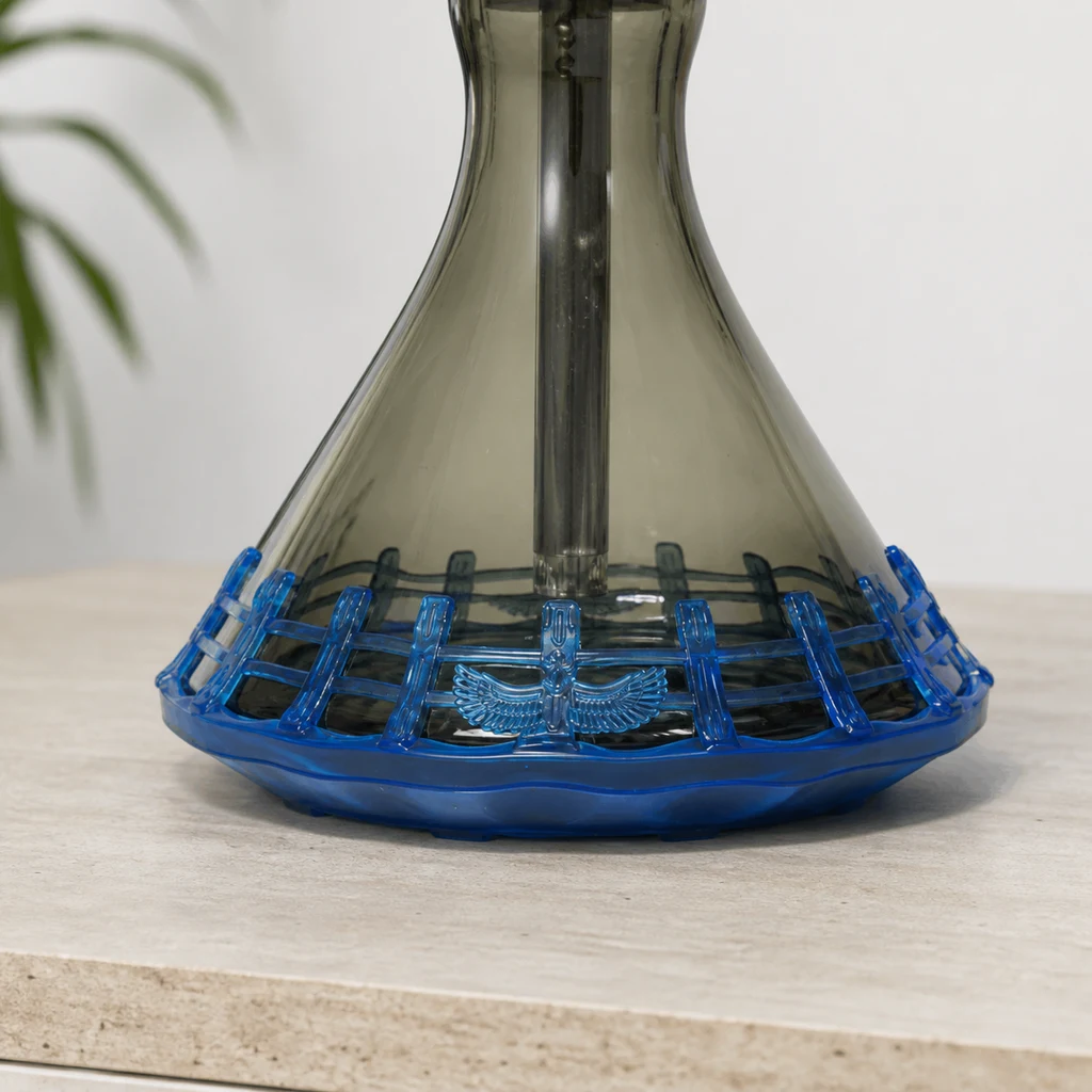 Detalle de un protector azul de silicona con diseño de rejilla y emblema alado, colocado alrededor de la base de una cachimba.