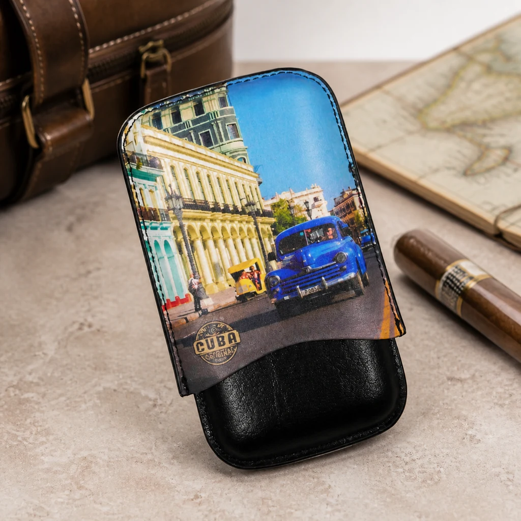 Estuche para puros Cuba negro con una escena urbana y un coche azul en la tapa, junto a un puro, un mapa y un bolso marrón.