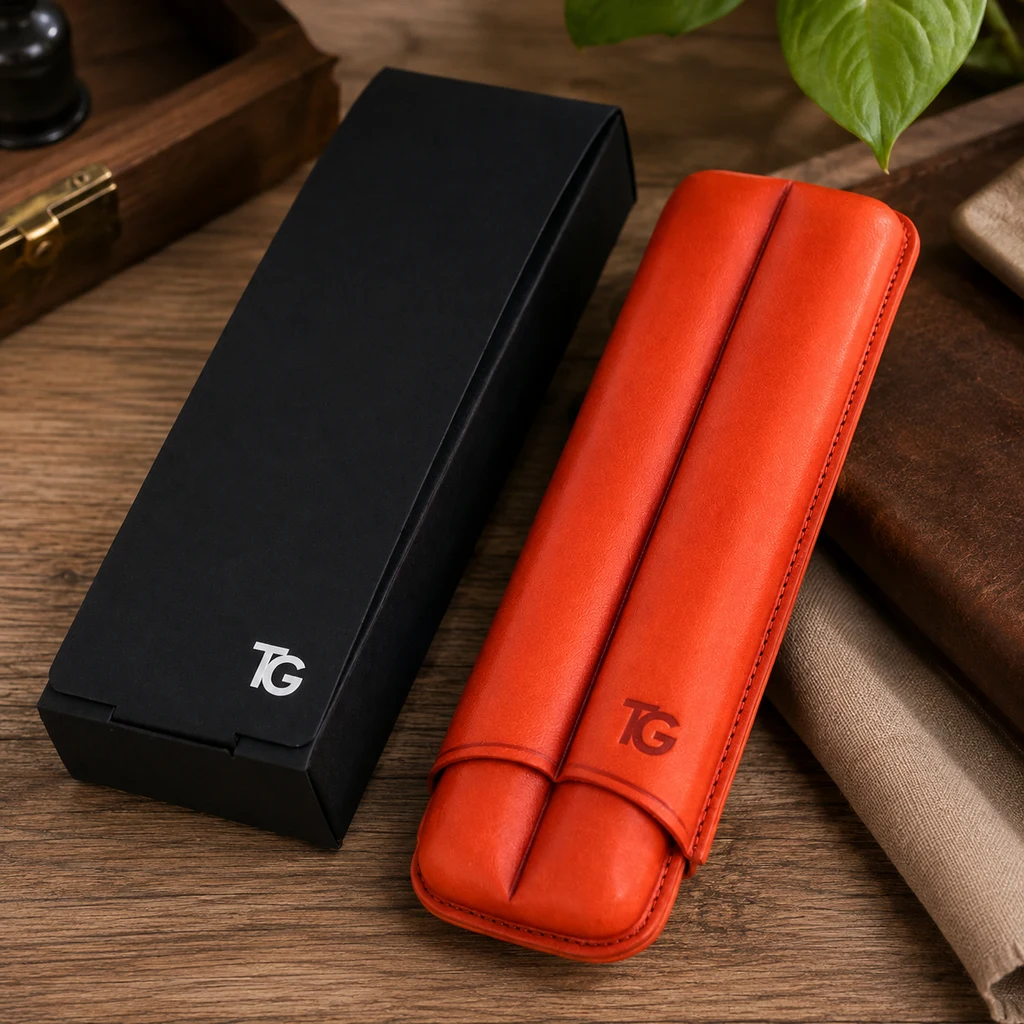 Estuche rojo anaranjado para puros, con costuras y relieve longitudinal, junto a una caja negra sobre una mesa de madera.
