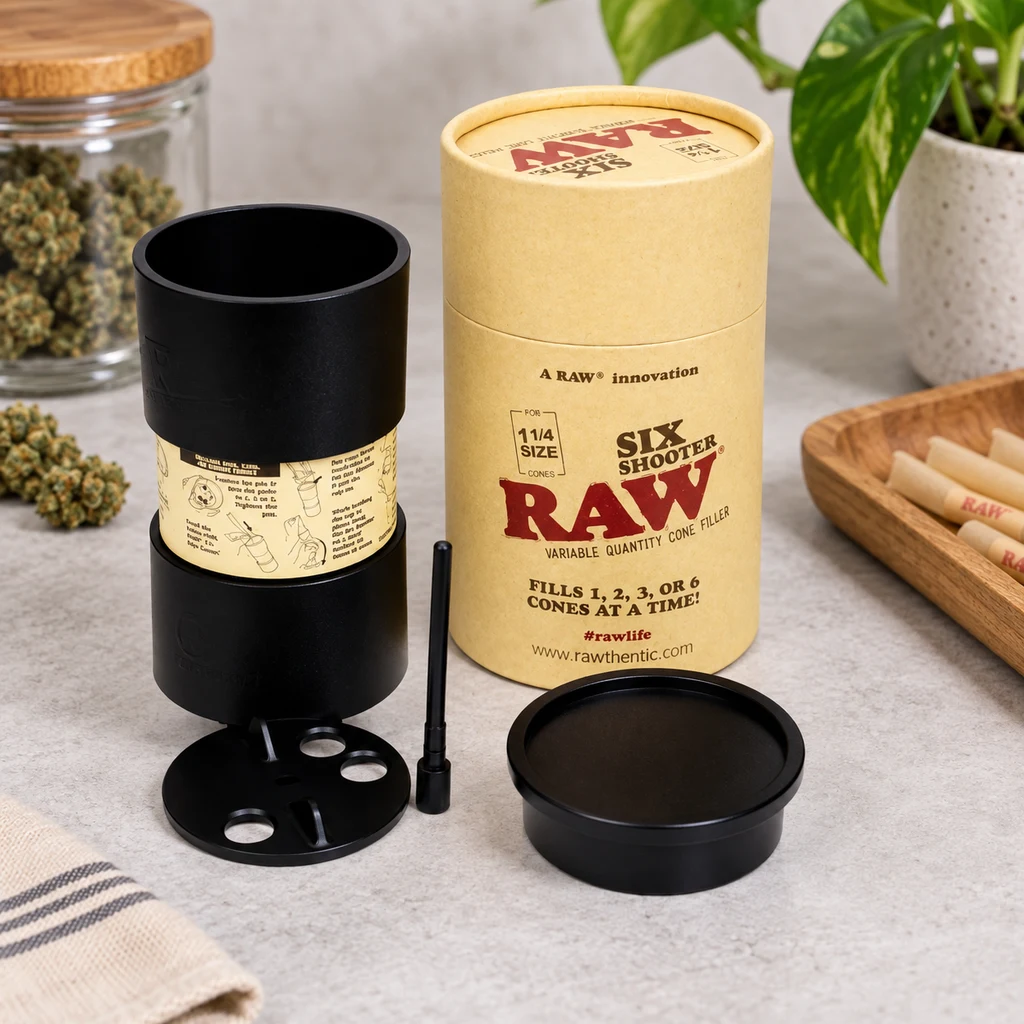 Escena generada del RAW Six Shooter 1 ¼ negro, con piezas separadas junto a su envase cilíndrico y una bandeja con conos.