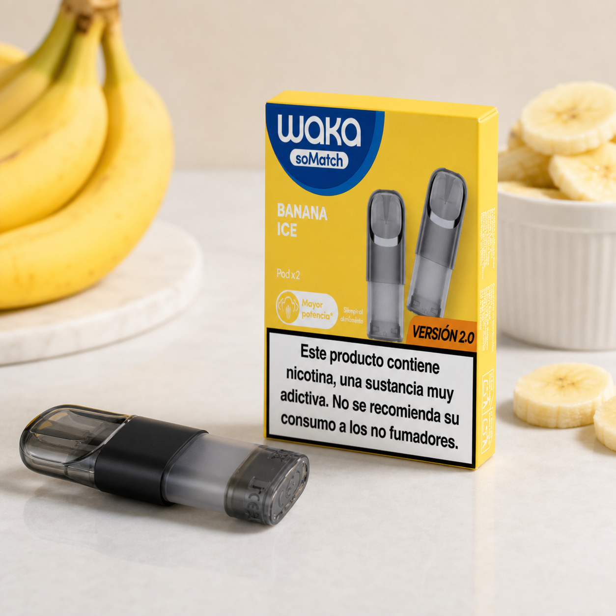 Cartucho Waka soMatch Banana Ice tumbado junto a su caja amarilla con aviso de nicotina, rodeado de plátanos y rodajas.