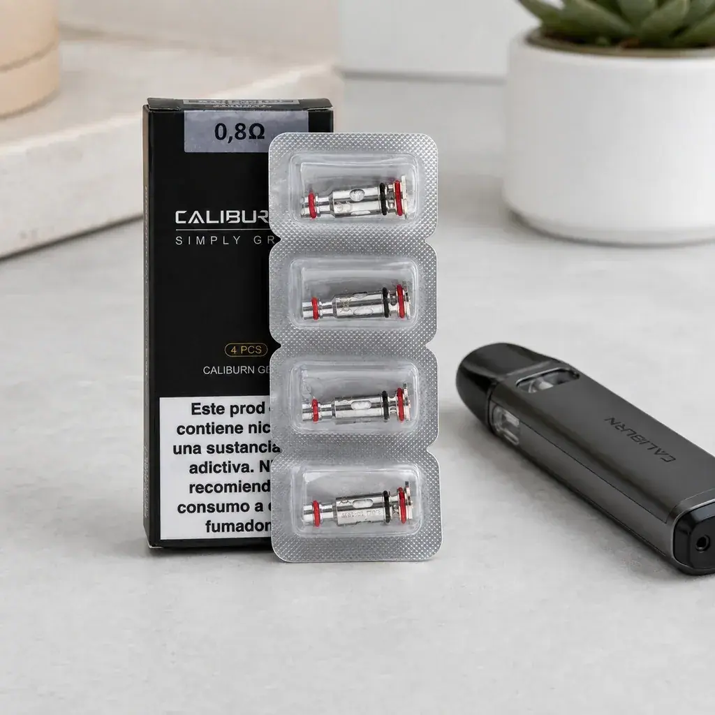 Resistencias Uwell Caliburn G en blíster, delante de una caja marcada 0,8 Ω y junto a un dispositivo negro sobre una mesa clara.