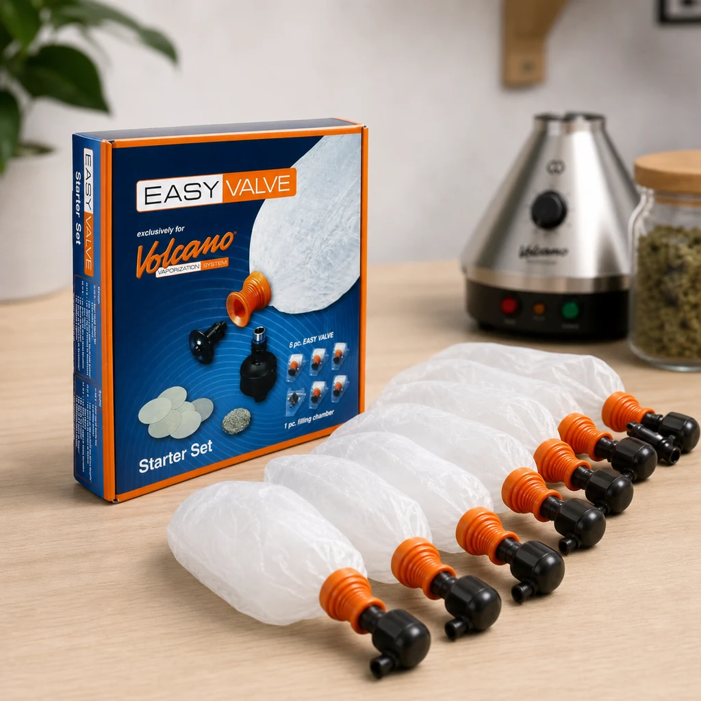 Bolsas Volcano Easy Valve con conectores naranjas y boquillas negras sobre una mesa, junto a una caja Starter Set y un vaporizador al fondo.