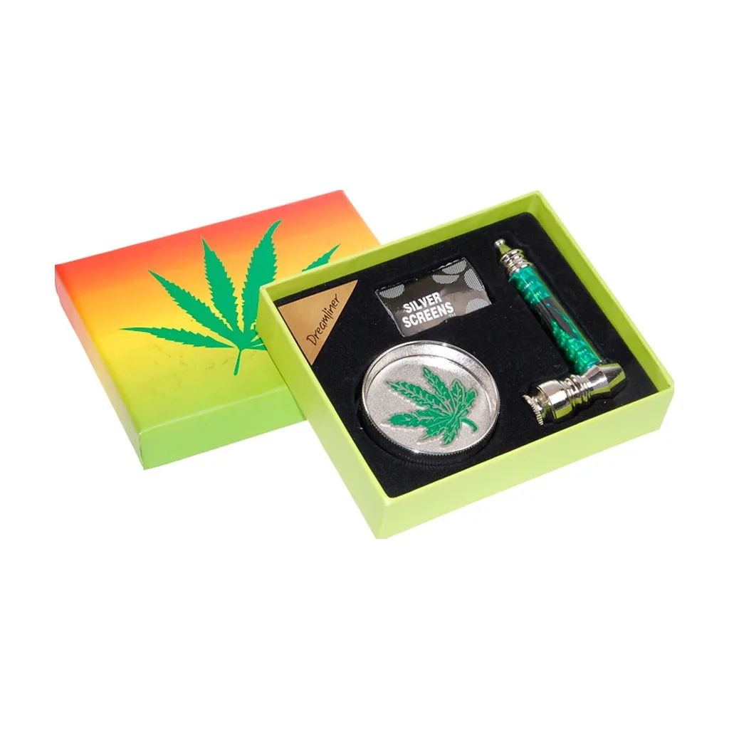 Caja verde abierta con pipa de mango verde, grinder plateado con hoja de cannabis y sobre de rejillas sobre un interior negro. Caja verde abierta con pipa de mango verde, grinder plateado con hoja de cannabis y sobre de rejillas sobre un interior negro.