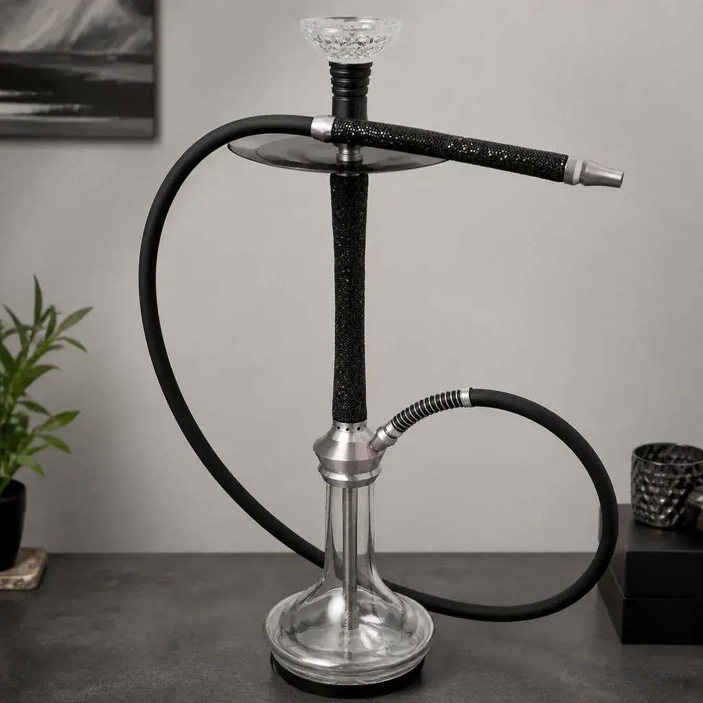Cachimba con base transparente, mástil negro, plato metálico y manguera negra curvada, con la boquilla apoyada en la parte superior.