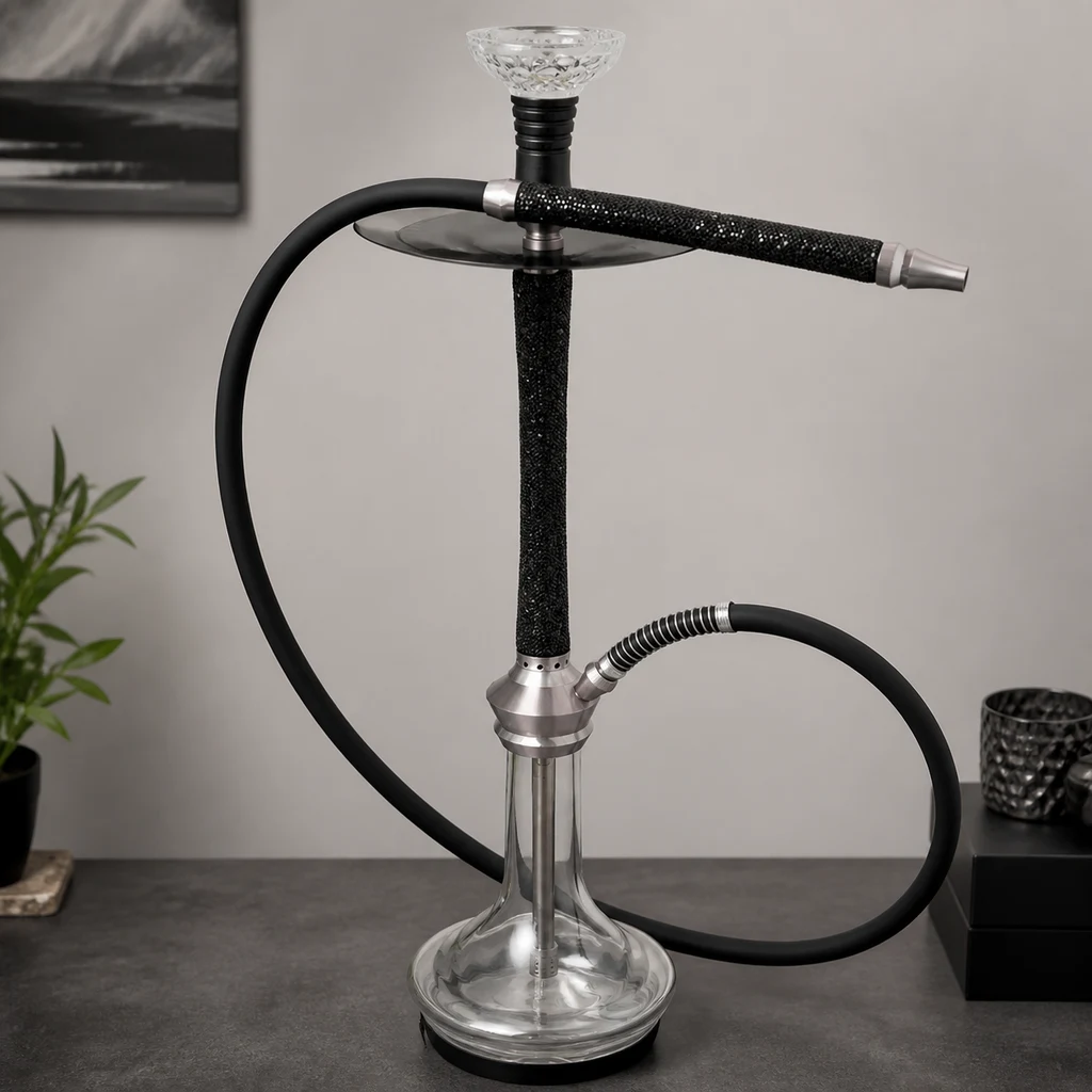 Cachimba con base transparente, mástil negro, plato metálico y manguera negra curvada, con la boquilla apoyada en la parte superior.