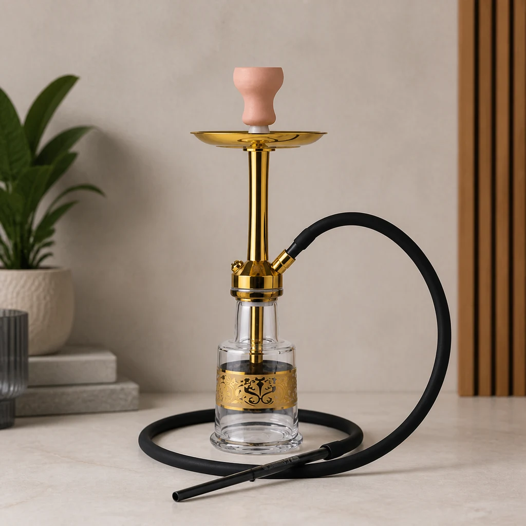 Cachimba Malik Guisser Gold de cuerpo dorado, base transparente y cazoleta rosa, con manguera negra enrollada sobre la mesa.