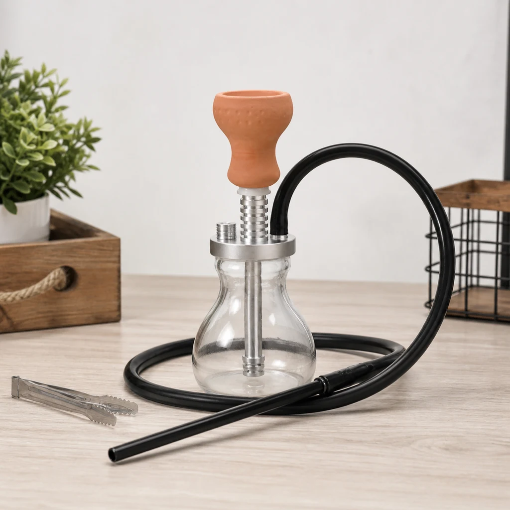 Cachimba Malik Lakhsas Silver con base transparente, cuerpo plateado, cazoleta naranja y manguera negra sobre una mesa junto a unas pinzas.