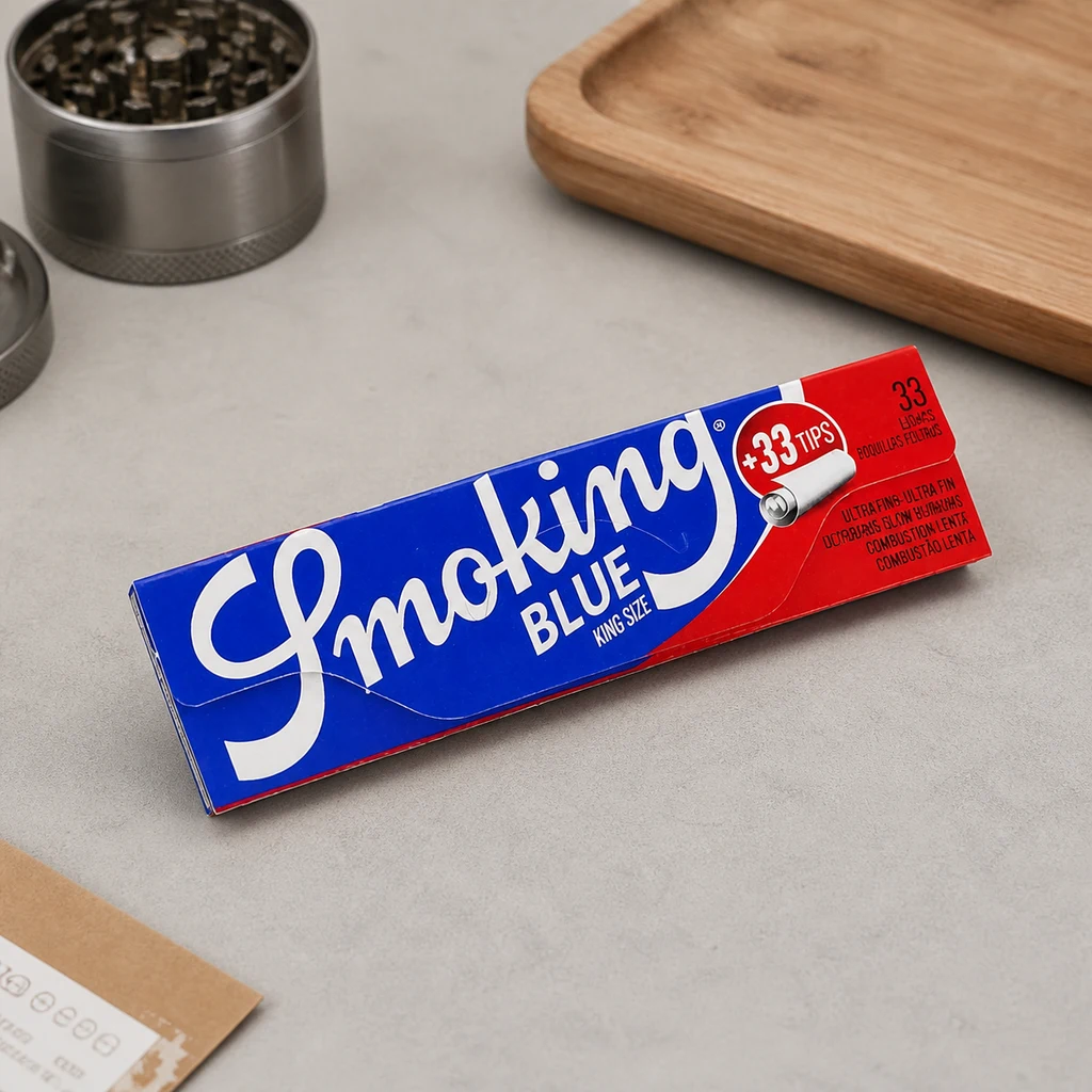Librillo Smoking Blue King Size con zona roja marcada +33 Tips, sobre una mesa junto a un grinder abierto y una bandeja de madera.