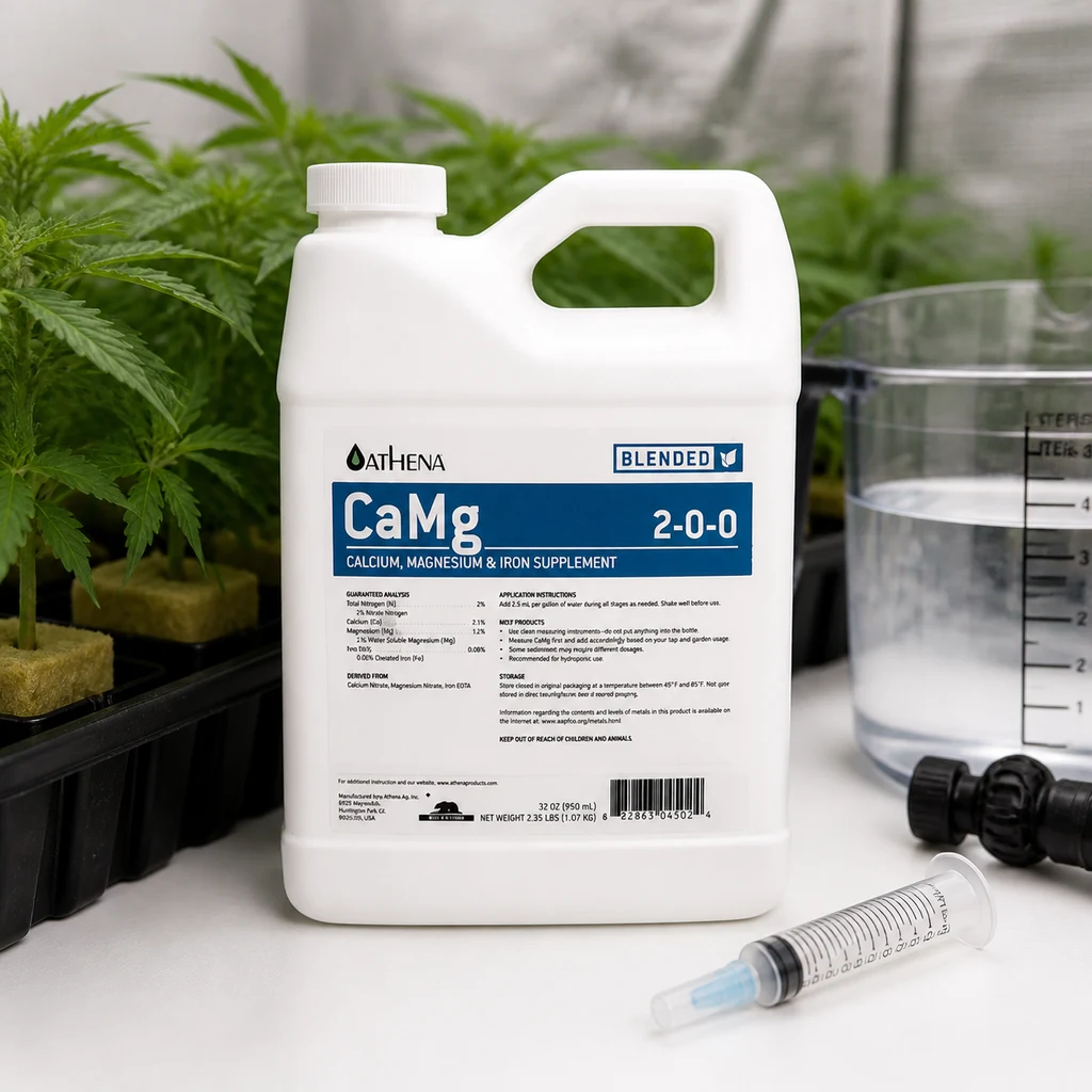 Envase blanco de suplemento CaMg Athena con asa y etiqueta azul, junto a plantas, una jarra graduada y una jeringa sobre la mesa.