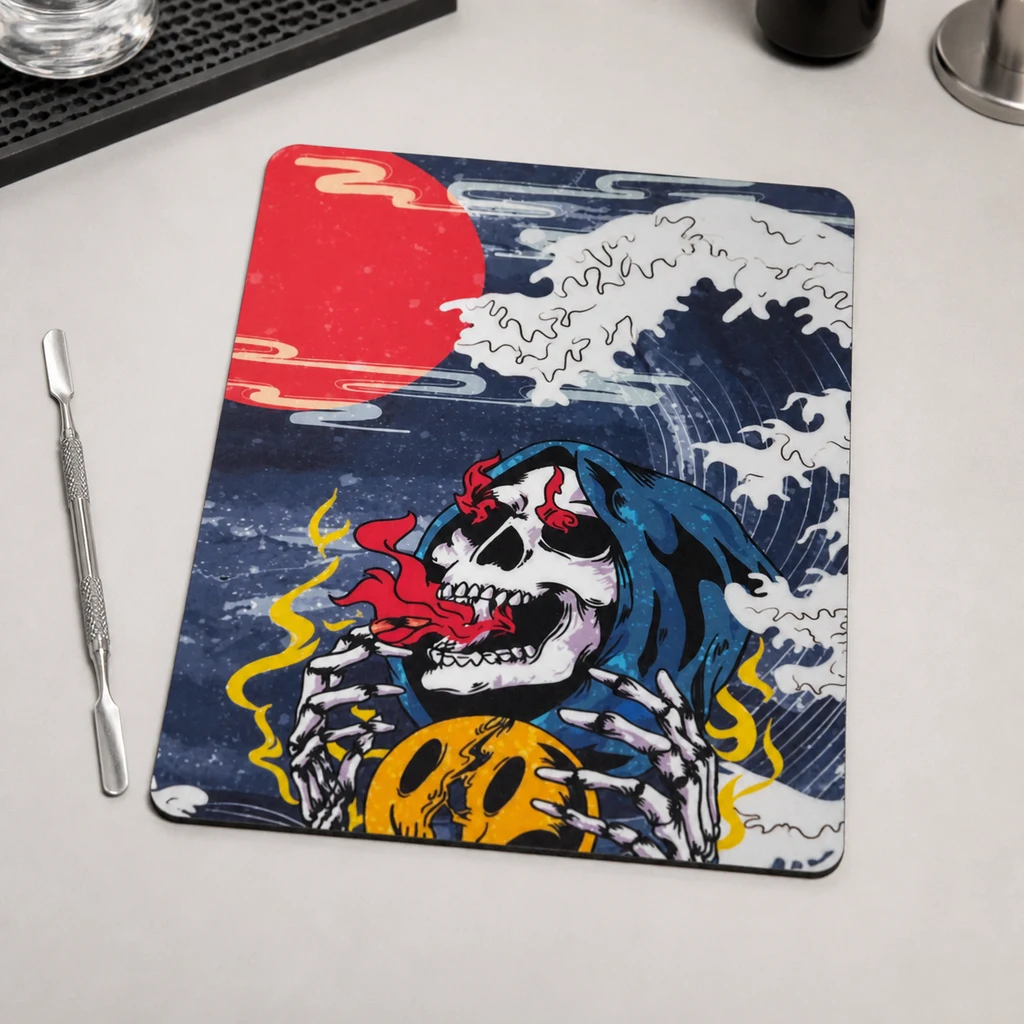 Estera Skull con una calavera encapuchada, olas y un sol rojo, sobre una encimera junto a una herramienta de doble punta.