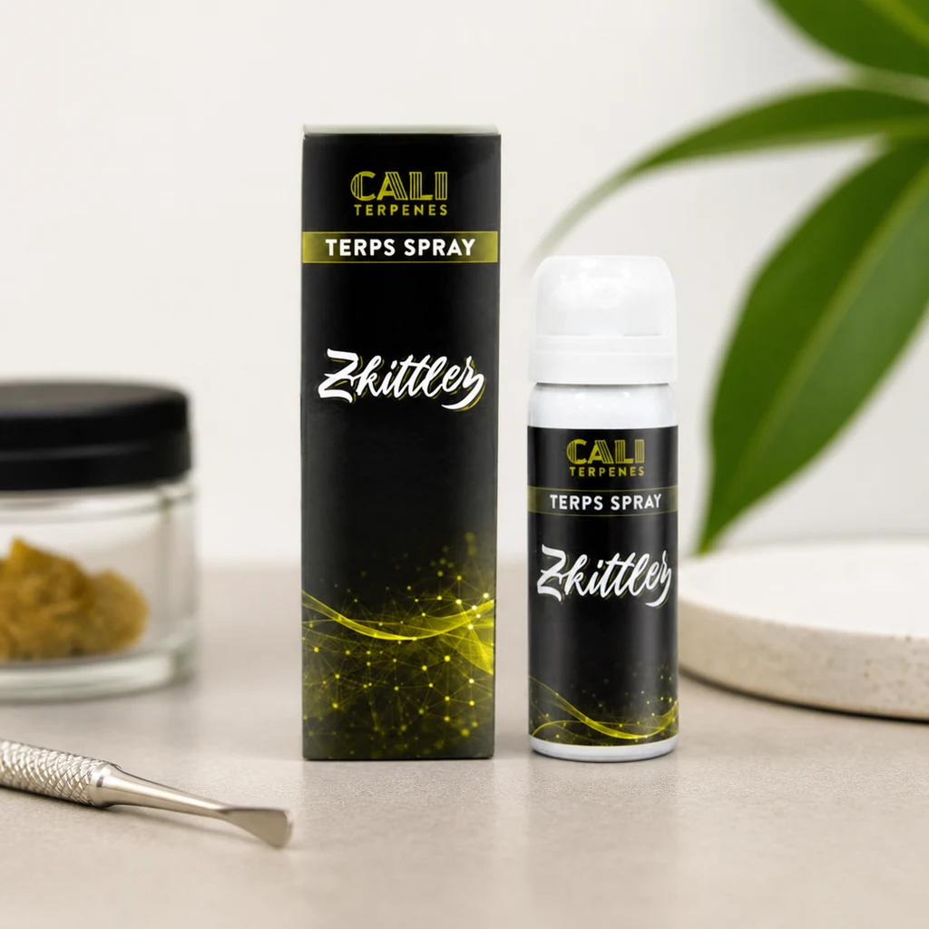 Spray Cali Terpenes con tapa blanca junto a su caja negra, ambos con la inscripción Zkittlez, sobre una mesa con un utensilio metálico.