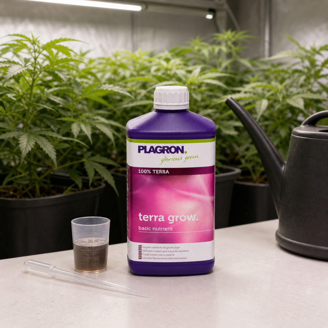 Botella morada de Terra Grow Plagron junto a un vaso dosificador, una pipeta y una regadera, con plantas al fondo.