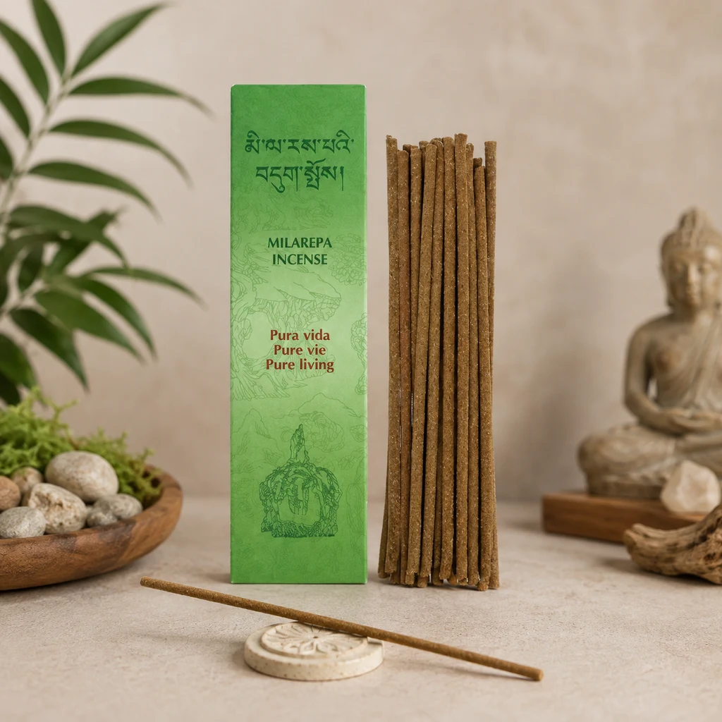 Incienso Tibetano Milarepa Pura Vida con caja verde, varillas verticales y una varilla sobre un soporte, junto a plantas y una figura de Buda.