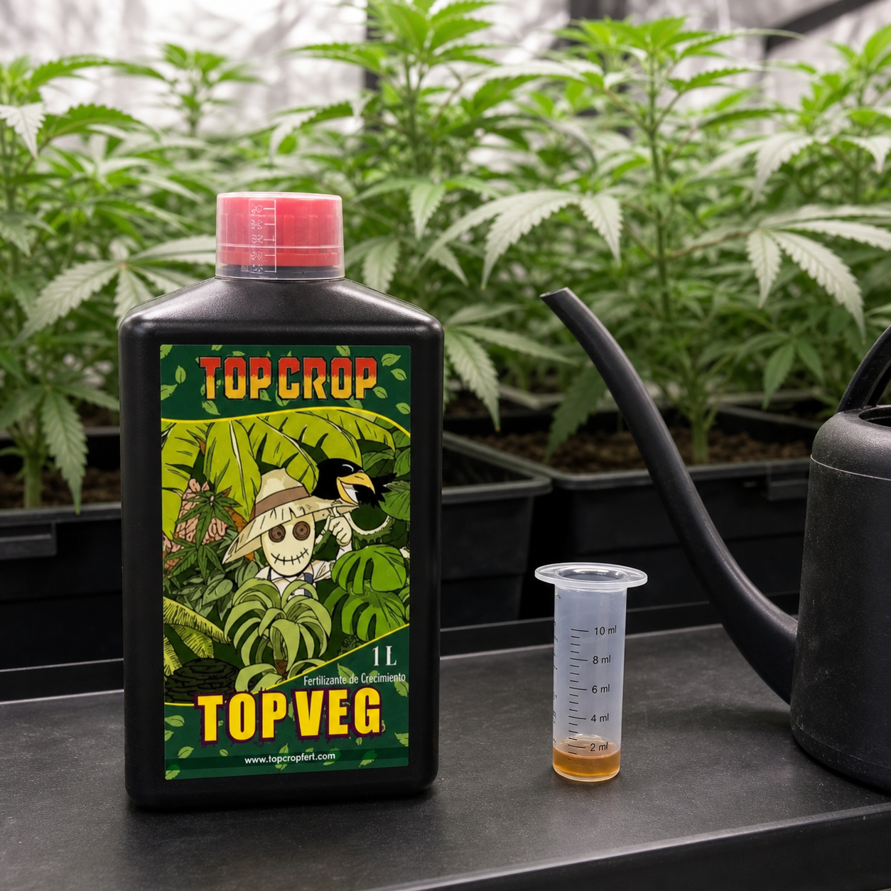 Botella de Top Veg de Top Crop con tapón rojo, junto a un vaso dosificador con líquido y una regadera, delante de plantas de cannabis.
