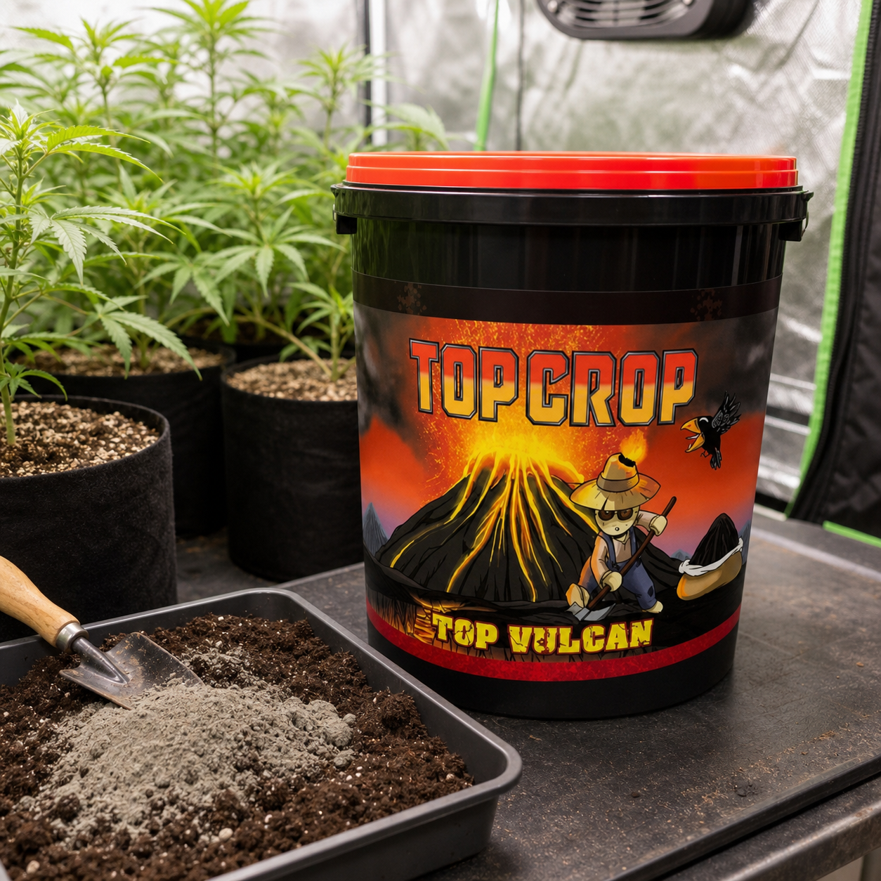 Cubo negro de Top Vulcan de Top Crop con tapa roja, junto a una bandeja con sustrato, polvo gris y una pala, con plantas al fondo. Cubo negro de Top Vulcan de Top Crop con tapa roja, junto a una bandeja con sustrato, polvo gris y una pala, con plantas al fondo.