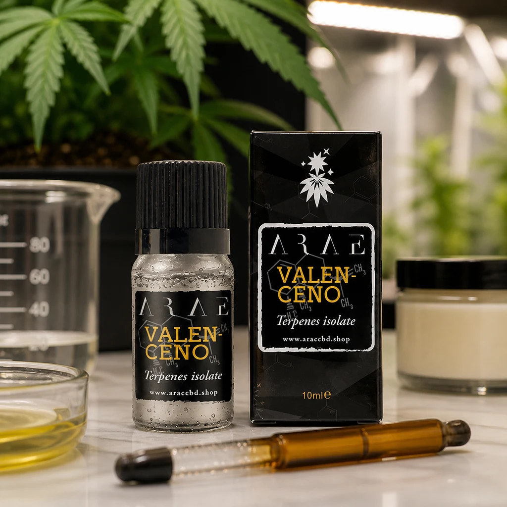 Frasco de Valenceno con tapón negro junto a su caja, con la inscripción Terpenes isolate, sobre una mesa con recipientes y plantas al fondo.