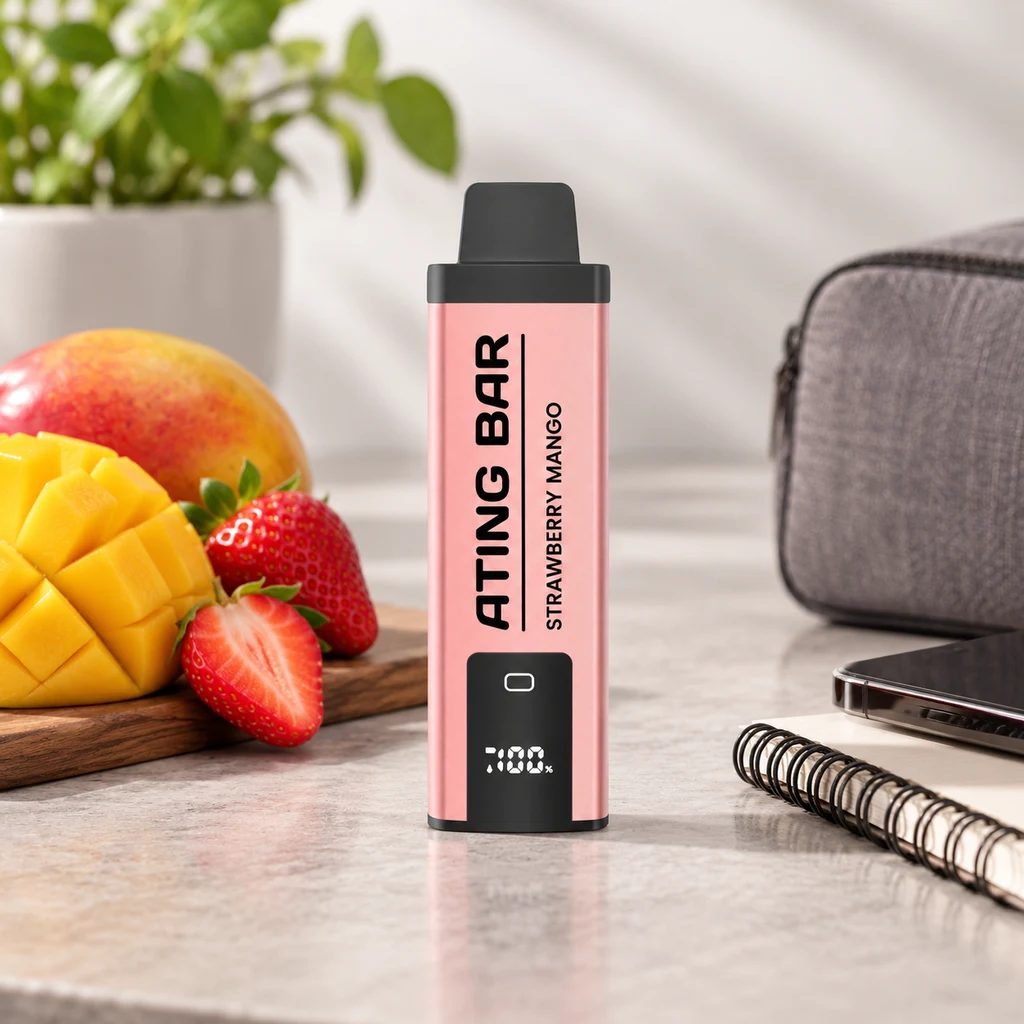 Vapeador rosa con boquilla negra, pantalla y texto «ATING BAR STRAWBERRY MANGO», sobre una encimera junto a fresas y mango.