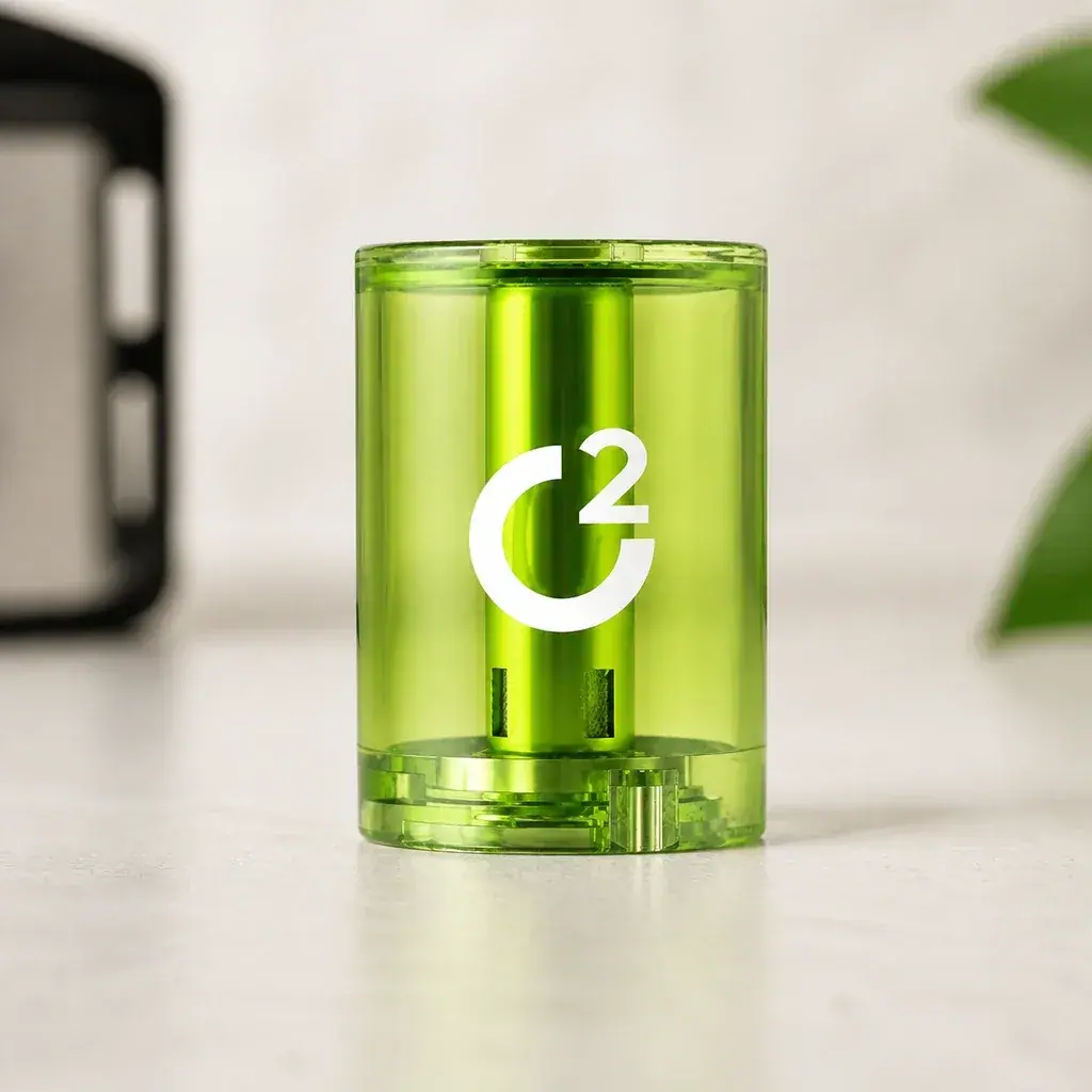 Cartucho Sweet Mint C2 cilíndrico y verde translúcido, con logotipo blanco, sobre una superficie clara con fondo desenfocado.