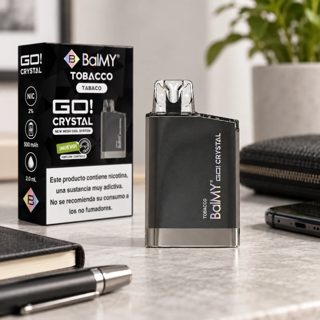 Vaper BalMY GO Crystal Tobacco negro con boquilla transparente, junto a su caja con advertencia de nicotina, sobre un escritorio.