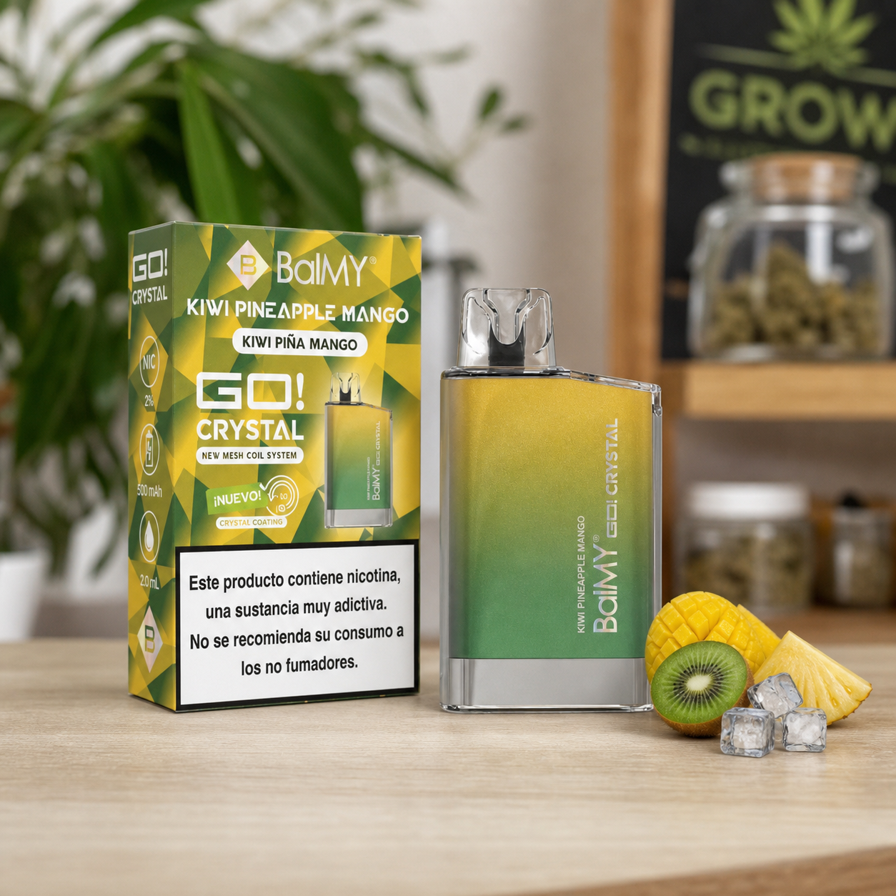 Vaper Balmy Go Crystal Kiwi Piña Mango en degradado amarillo y verde junto a su caja, fruta cortada y hielo sobre una mesa.