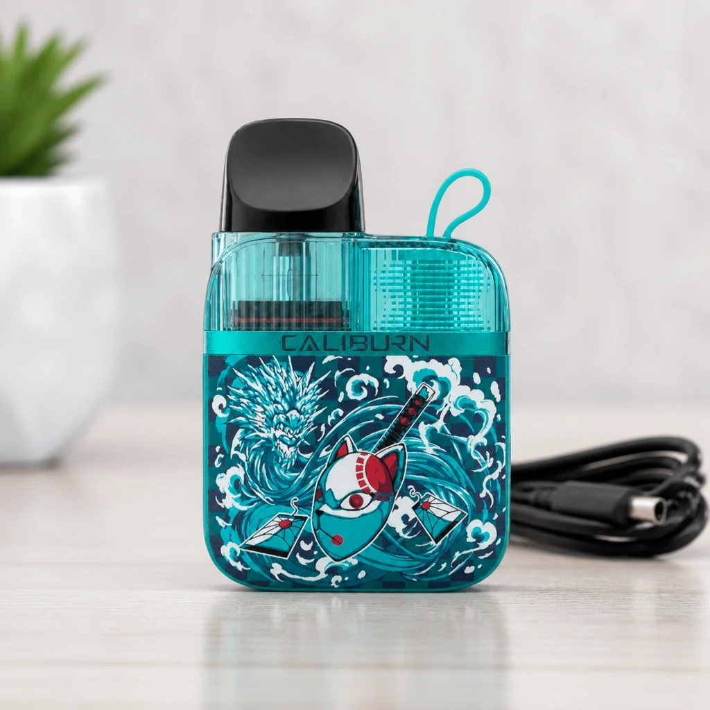 Vaper Caliburn Koko GK3 Water turquesa con boquilla negra y dibujos de olas y una máscara, sobre una mesa junto a un cable.