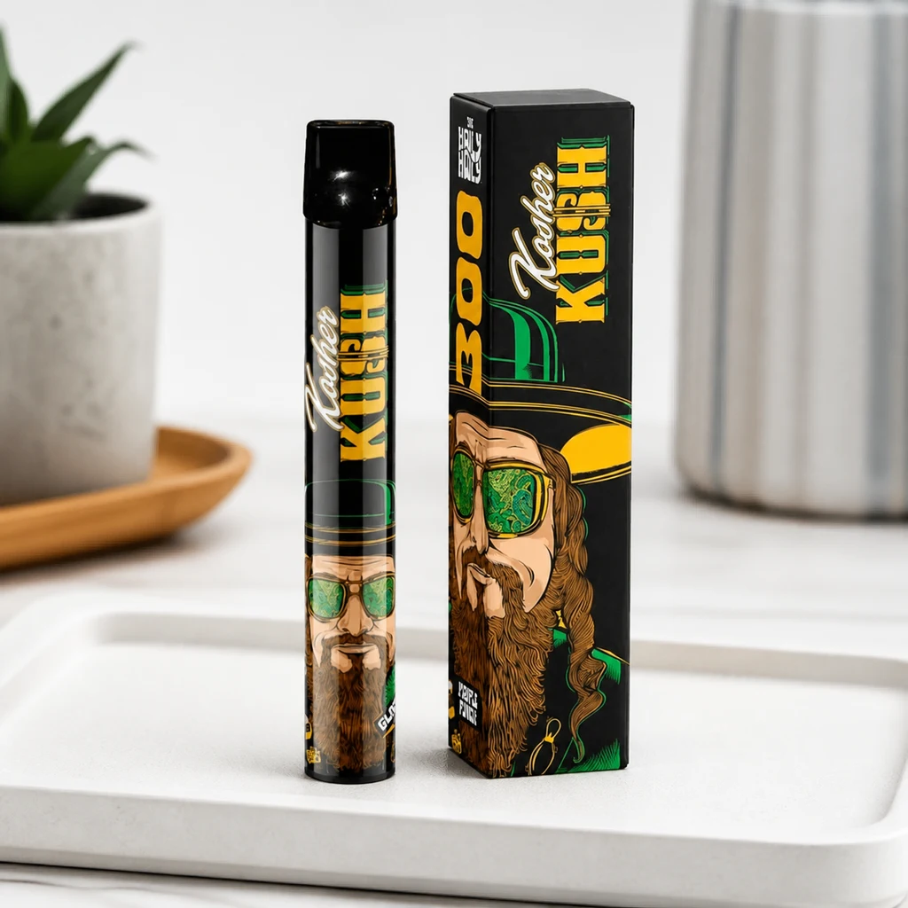 Vaper Kosher Kush negro junto a su caja, con letras amarillas y un personaje barbudo con gafas verdes, sobre una bandeja blanca. Vaper Kosher Kush negro junto a su caja, con letras amarillas y un personaje barbudo con gafas verdes, sobre una bandeja blanca.