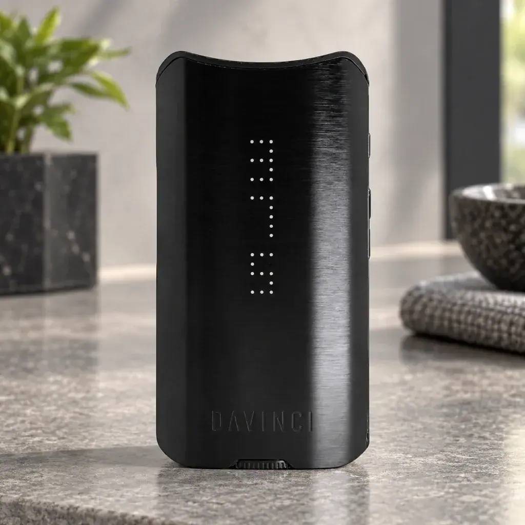 Vaporizador DaVinci IQ3 Onyx negro en posición vertical, con indicadores luminosos de puntos y logotipo frontal, sobre una encimera gris.