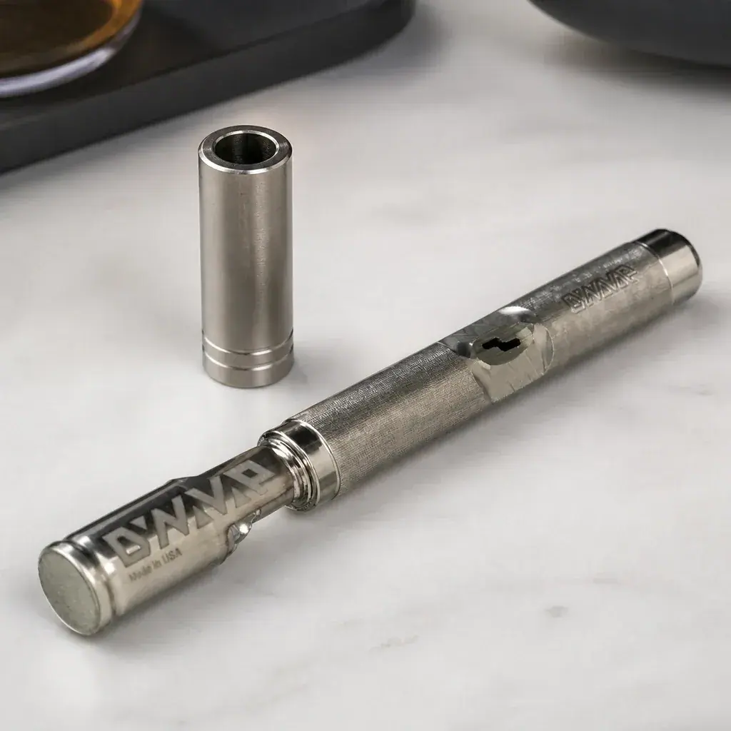 Escena generada del vaporizador Dynavap M7 metálico sobre una superficie clara, con el capuchón retirado colocado en vertical.