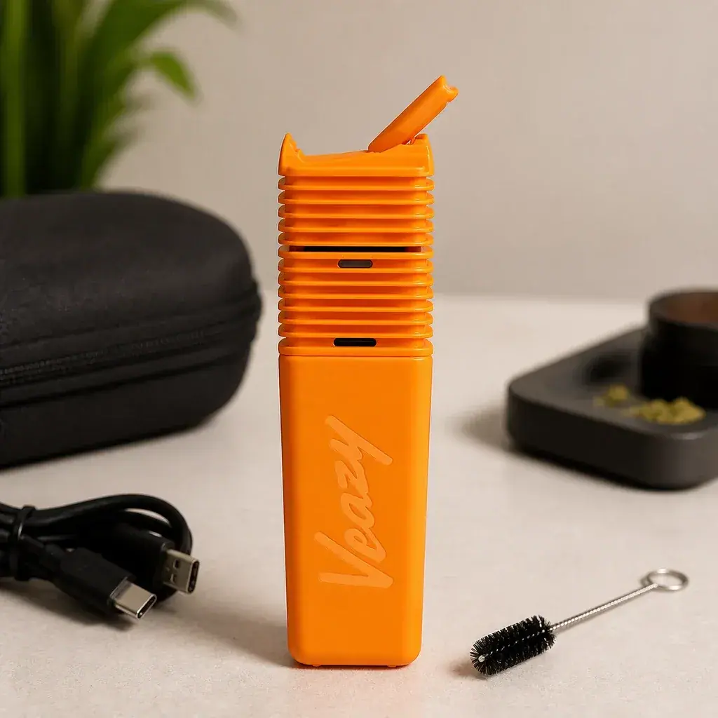 Vaporizador Veazy naranja con cuerpo acanalado y boquilla levantada, junto a un estuche negro, cable USB y cepillo.