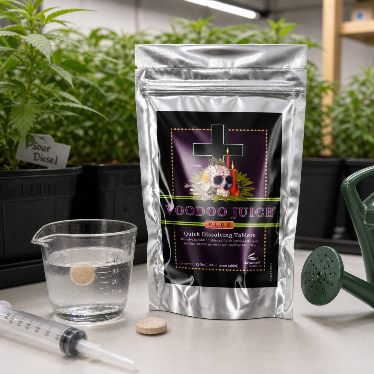 Bolsa plateada de Voodoo Juice Plus de Advanced Nutrients junto a comprimidos, un vaso con agua, una jeringa y una regadera, con plantas al fondo.